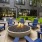 a group of blue chairs around a fire pit outside a building